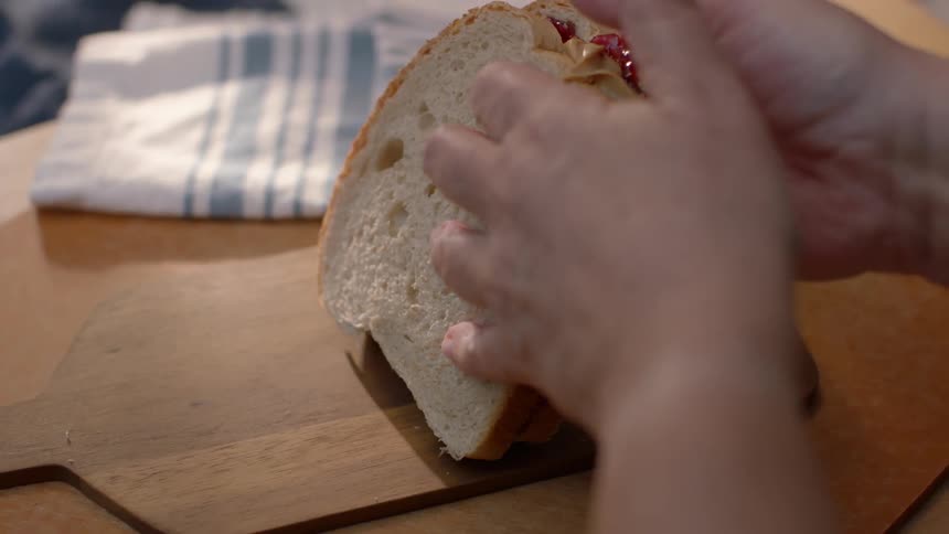 Person puts a peanut butter and jelly sandwich together
