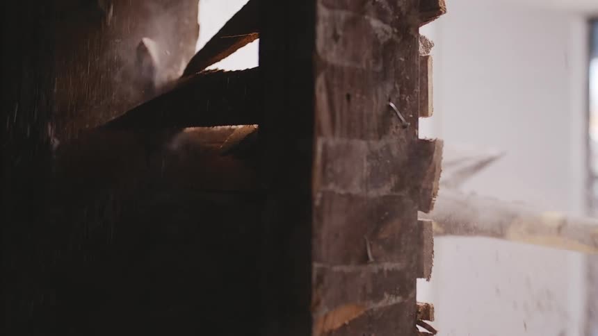 A sledgehammer forcefully breaks through a wooden wall in dramatic slow motion, sending splinters flying