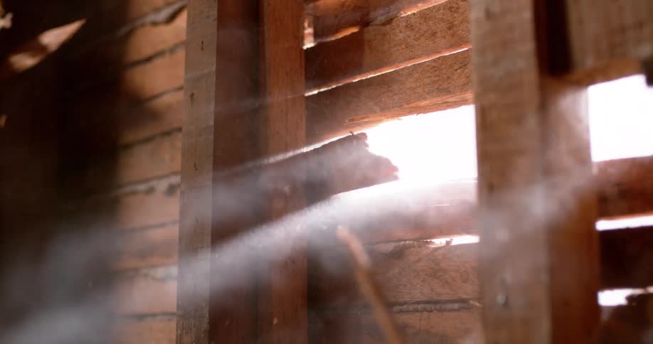 Dramatic slow motion close-up of a power tool breaking through a wooden slat wall, with dust and splinters catching the light
