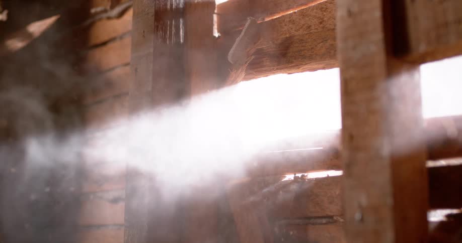Dramatic slow motion footage shows a sledgehammer breaking through wooden slats, creating a cloud of dust and debris