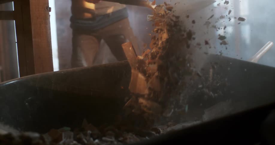 Extreme slow motion close up of a construction worker shoveling demolition rubble into a wheelbarrow