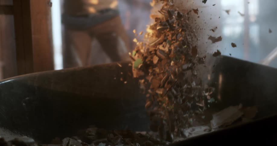 A construction worker shovels debris from a demolition site into a wheelbarrow in dramatic super slow motion