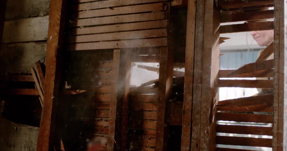 Super slow motion footage captures a lath and plaster wall being smashed open, sending debris flying towards the camera during a home demolition
