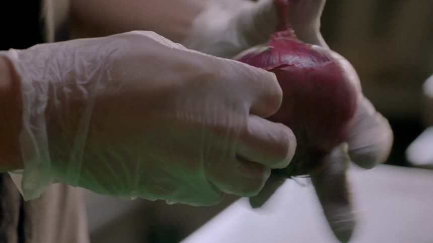A man is peeling a red onion