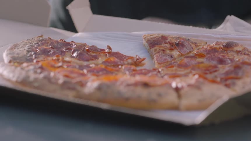 People taking slices from a pizza pie