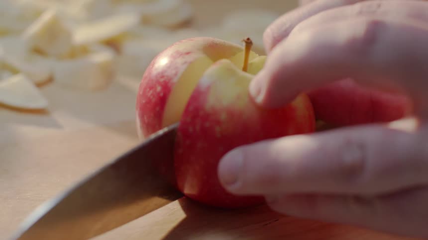 A person is cutting an apple with a large knife