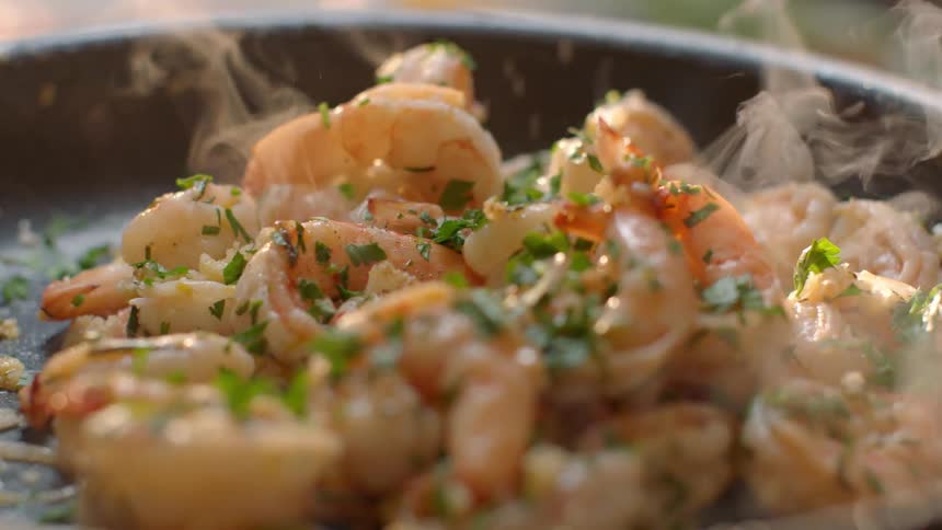 Shrimp is being cooked in a black pan