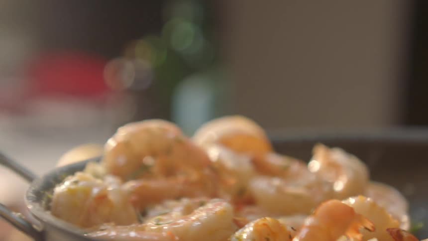 Shrimp is flipped in a pan as it cooks