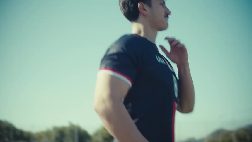 In slow motion, a determined soccer player in a USA jersey warms up, claps for his team, and jogs into the bright sun
