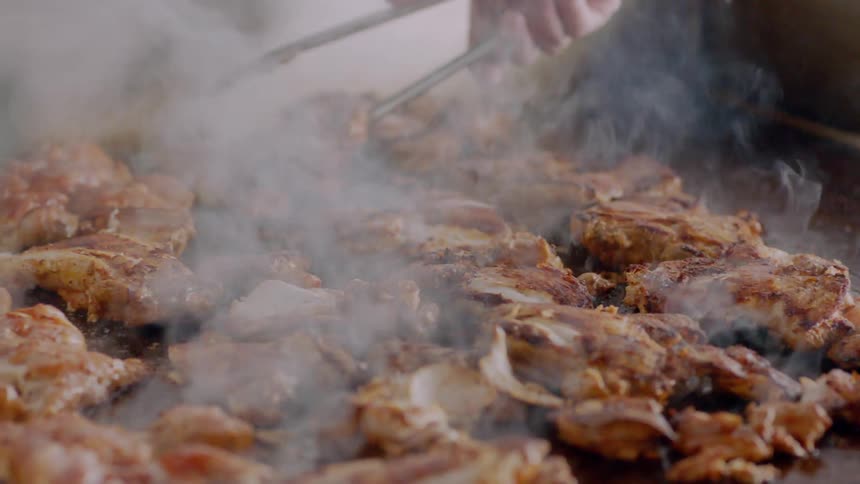 Person cooking pieces of chicken on a griddle