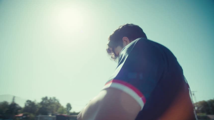 Slow motion tracking shot of a male soccer player in a USA jersey walking across a sunny field