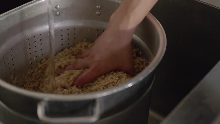 A person washes rice in a colander