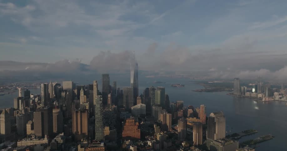 A majestic wide aerial view of the Lower Manhattan skyline as clouds roll over the skyscrapers during a beautiful morning