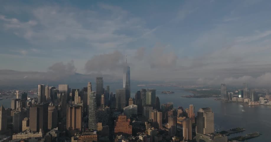 A static aerial view of the Lower Manhattan skyline with the One World Trade Center shrouded in morning clouds