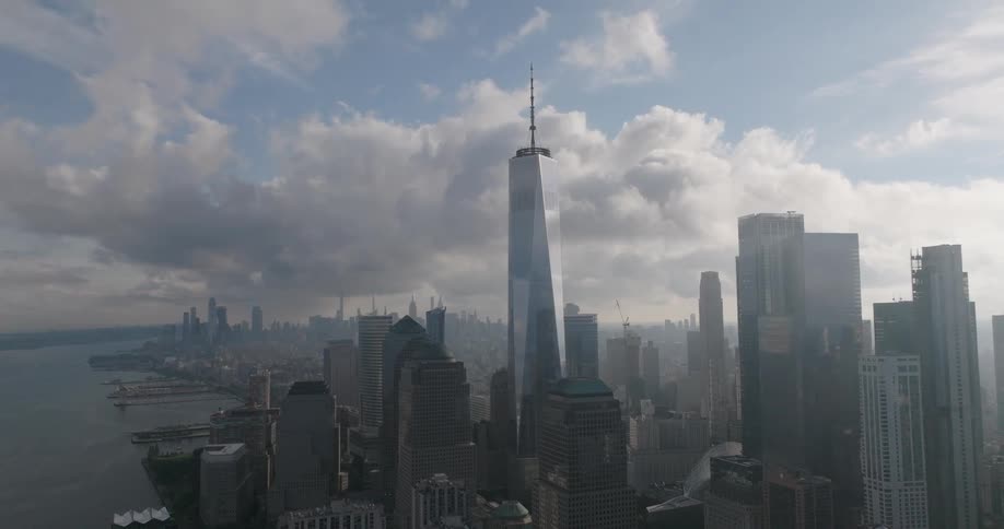 Dramatic clouds roll over the iconic One World Trade Center and the Lower Manhattan skyline in a slow pull-back aerial shot