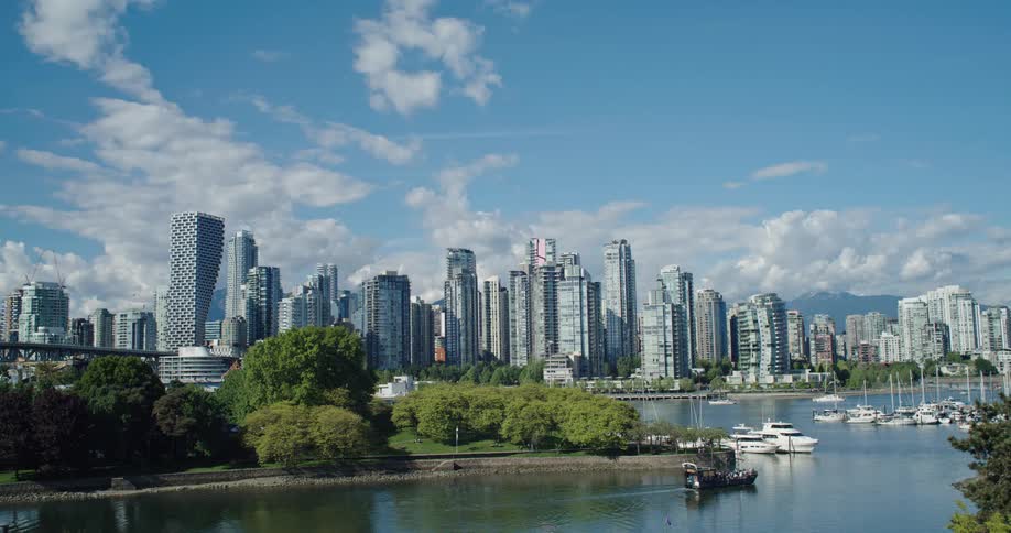 A water taxi sails across the harbor in front of the modern Vancouver, Canada skyline on a beautiful sunny day