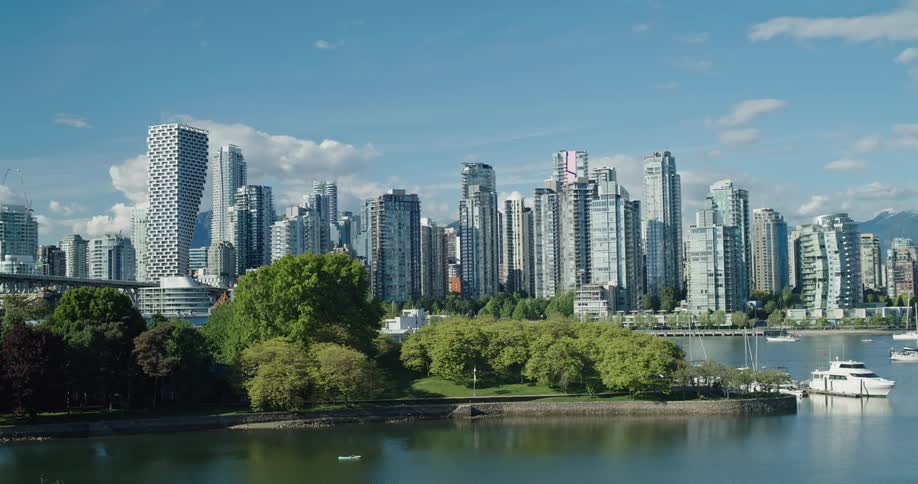The picturesque Vancouver skyline stands tall over the tranquil waters of False Creek on a bright and sunny day