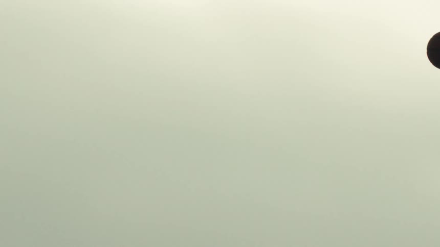 A silhouetted basketball player takes a shot over a defender in dramatic super slow motion