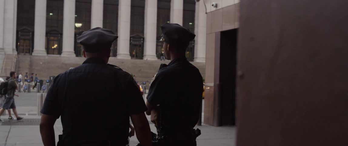 Two cops stand and watch traffic and pedestrians