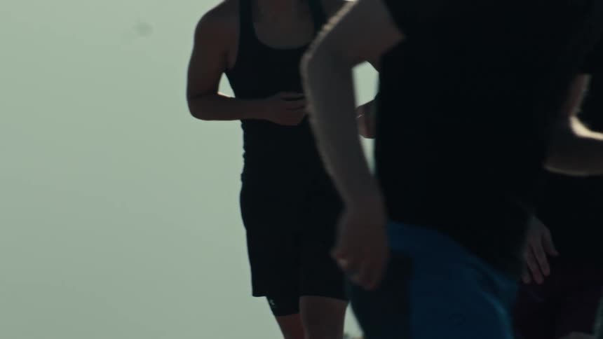 A group of diverse athletes play basketball in slow motion, silhouetted against the hazy sky