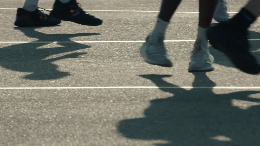A slow-motion close-up of the feet and shadows of athletes running together on a track