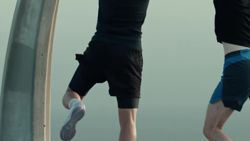 In slow motion, a basketball player jumps to make a shot while being closely guarded by a defender during a pickup game