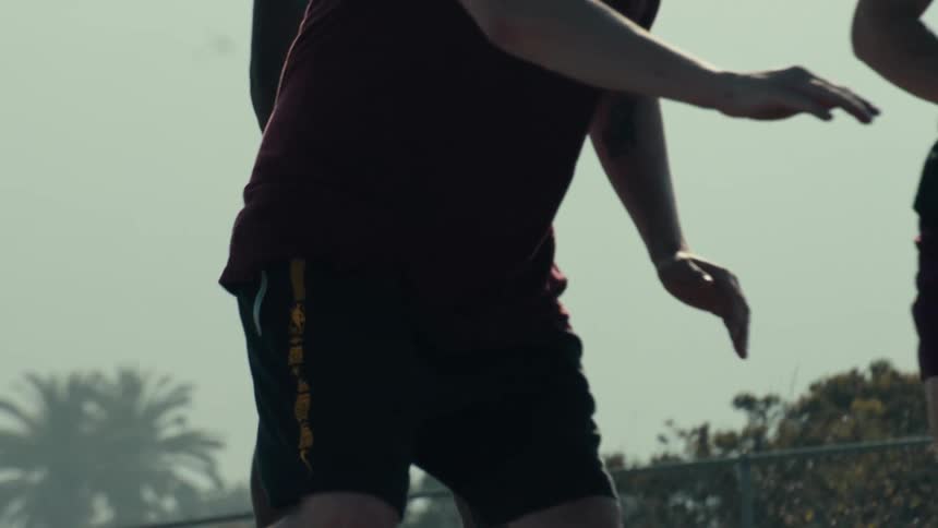 A close-up slow motion pan across several men playing a competitive game of basketball on an outdoor court