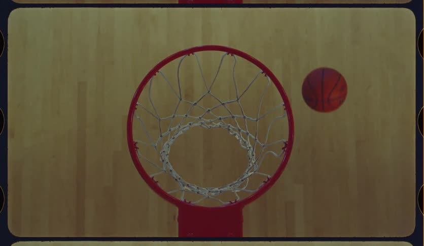 A basketball swishes through the net in slow motion as seen from a top-down perspective on a vintage film reel