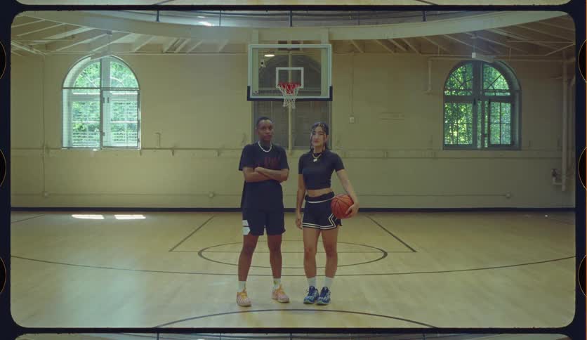 Full shot of two young confident basketball players standing together on an indoor court and looking at the camera