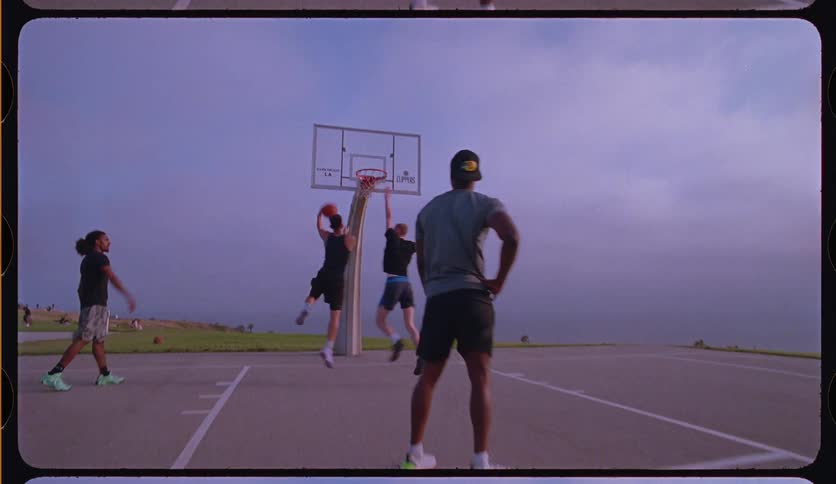 Slow motion of a young man making a layup shot during a pickup basketball game with friends on an outdoor court
