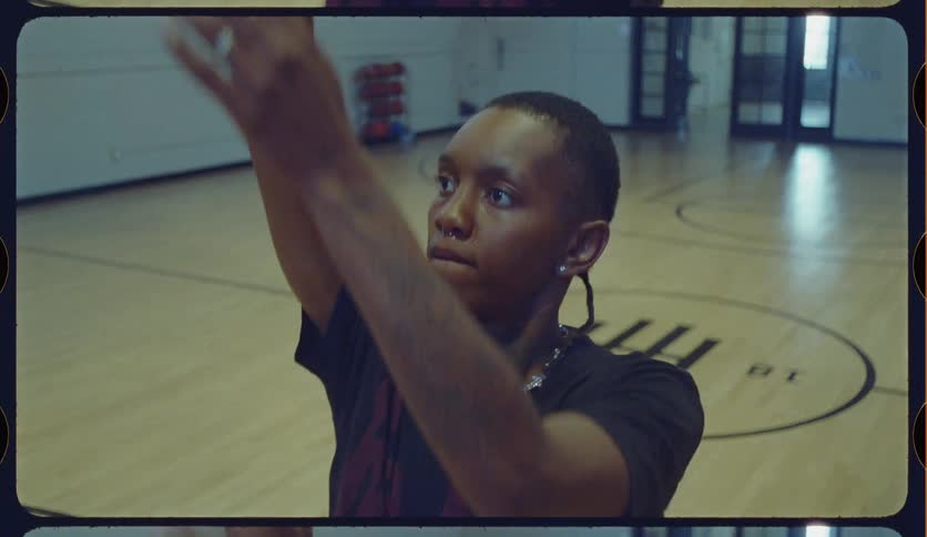 A focused young basketball player practices shooting free throws in a gym in this vintage film-style shot