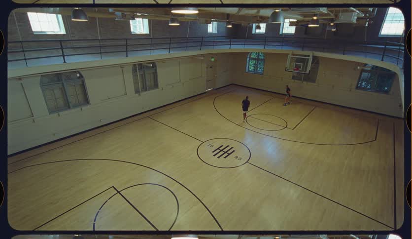 High angle shot of a man and woman casually playing basketball together on a vintage indoor court