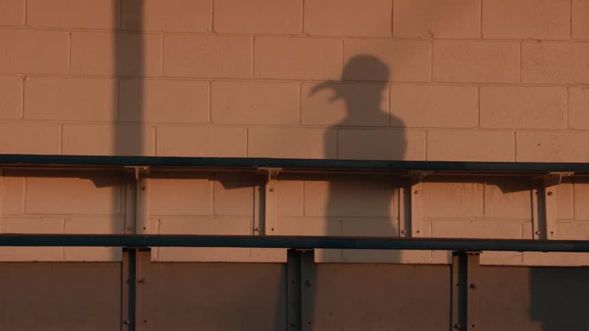 The shadow of a person magically transforms and plays with a floating ball against a wall in super slow motion