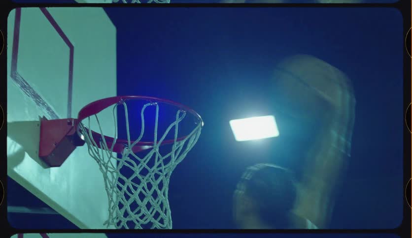 Slow-motion slam dunk on an outdoor basketball court at night with a vintage film look