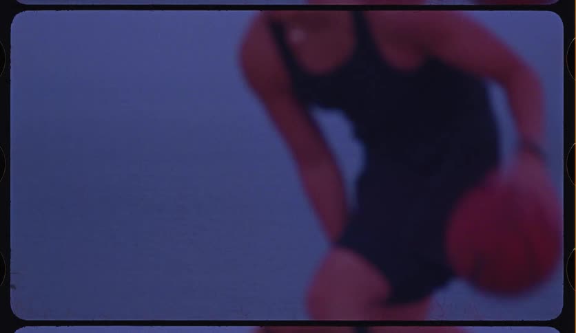 Out-of-focus Super 8mm film style shot of a person in athletic wear dribbling a basketball against a blue background