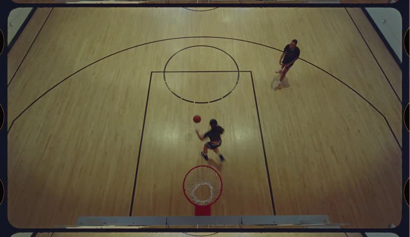 High-angle view of two friends playing basketball, dribbling, and scoring in slow motion on an indoor court
