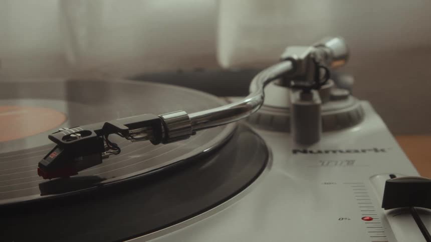 A close-up shot of a turntable's stylus playing a spinning vinyl record