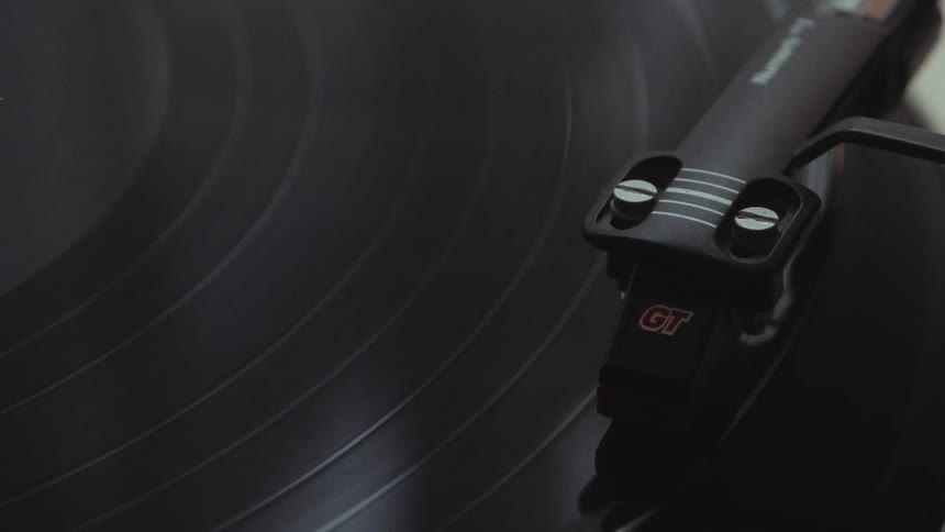 A detailed close-up shows a vinyl record spinning on a classic turntable