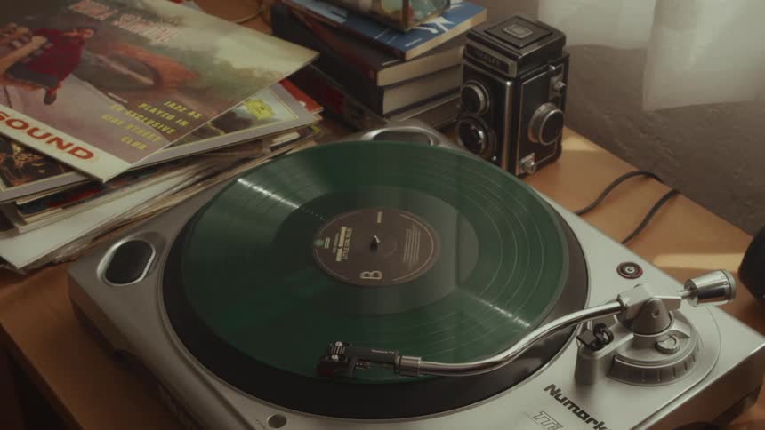A vintage scene features a green record playing on a turntable surrounded by old magazines and a retro camera