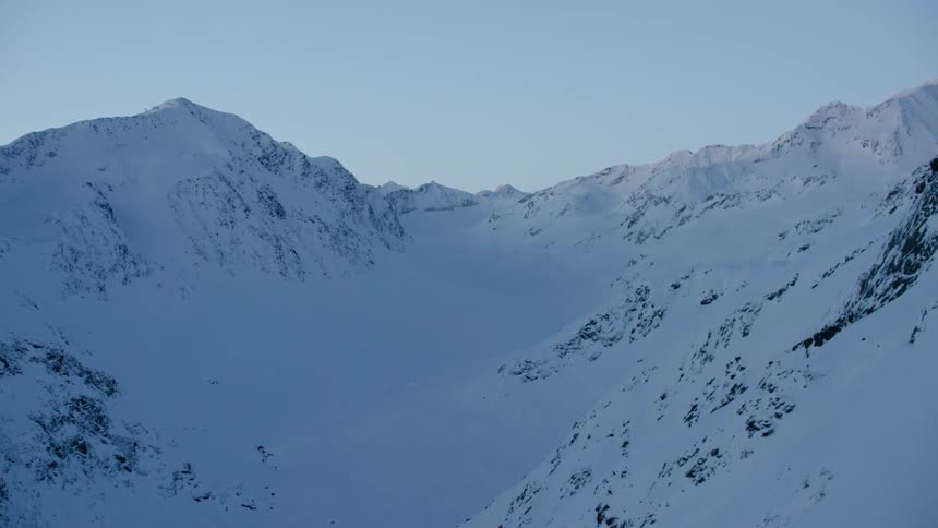 Shadow covers the valley of a snow-covered mountain range on a sunny day