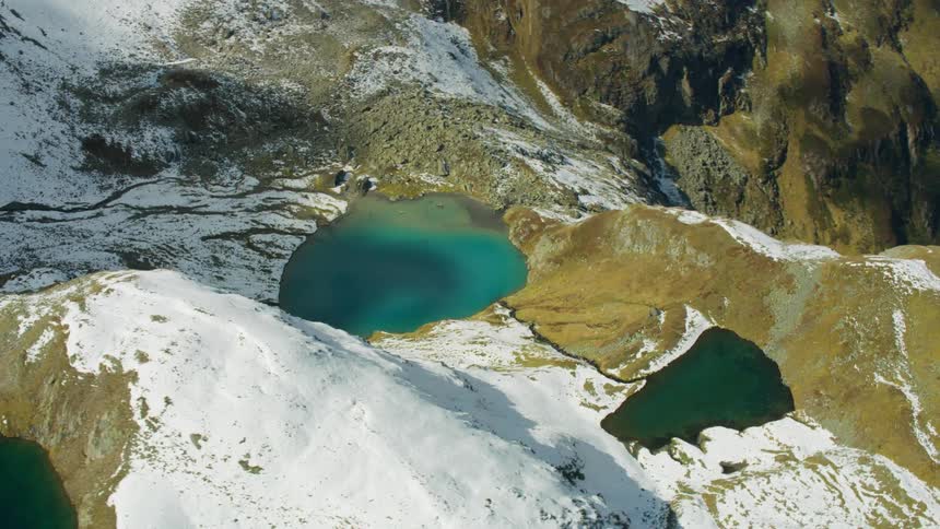 Lakes are shown on the side of a snowy mountain