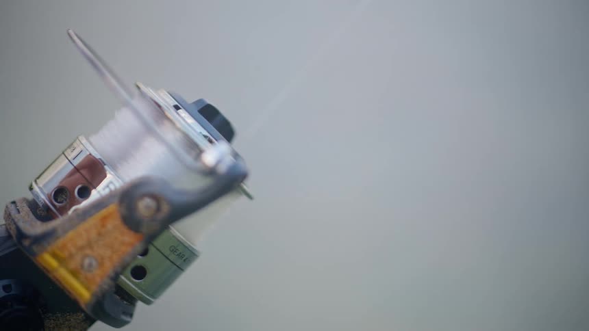 Extreme close-up of a sandy fishing reel casting a line in super slow motion