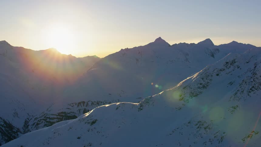 Sunlight shines over the peak of snowy mountains