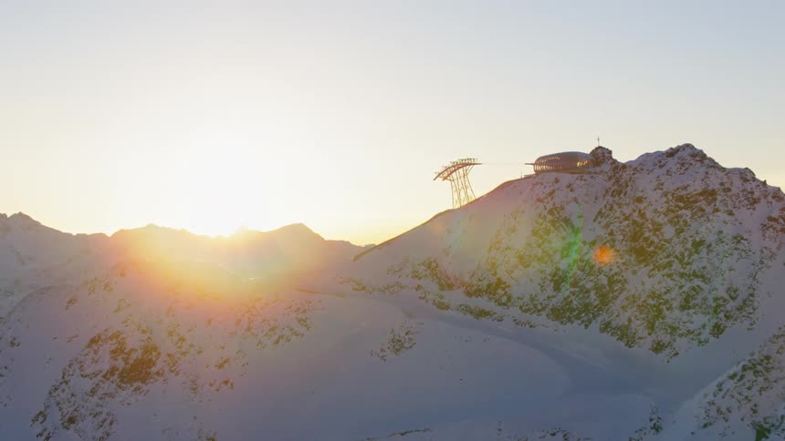 Sunlight shines over a snowy mountain ridge