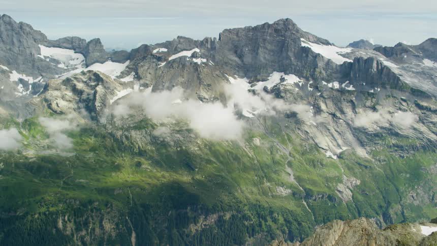 Clouds hover below the peaks of a mountain range