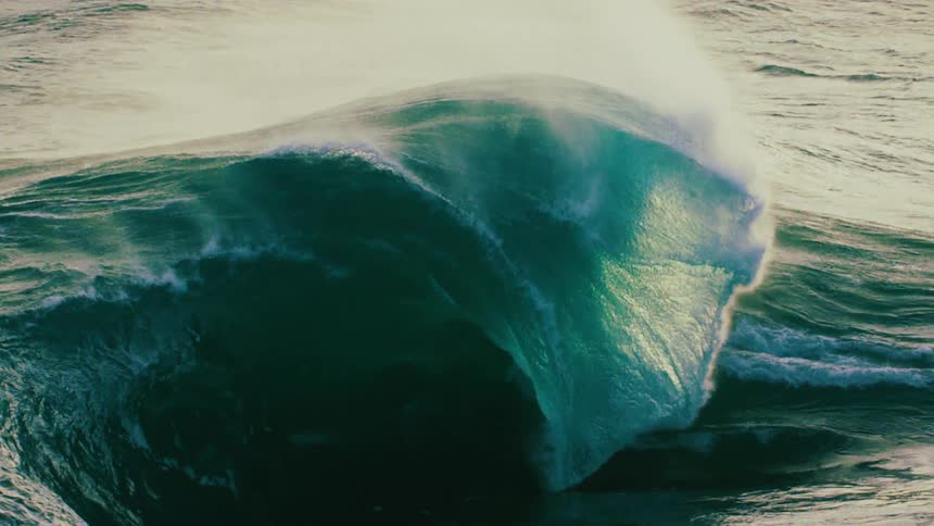 A massive, powerful ocean wave builds and crests in dramatic slow motion before breaking with incredible force