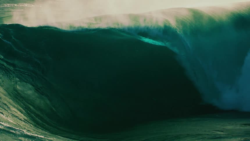 A massive, powerful ocean wave curls into a perfect barrel in dramatic slow motion
