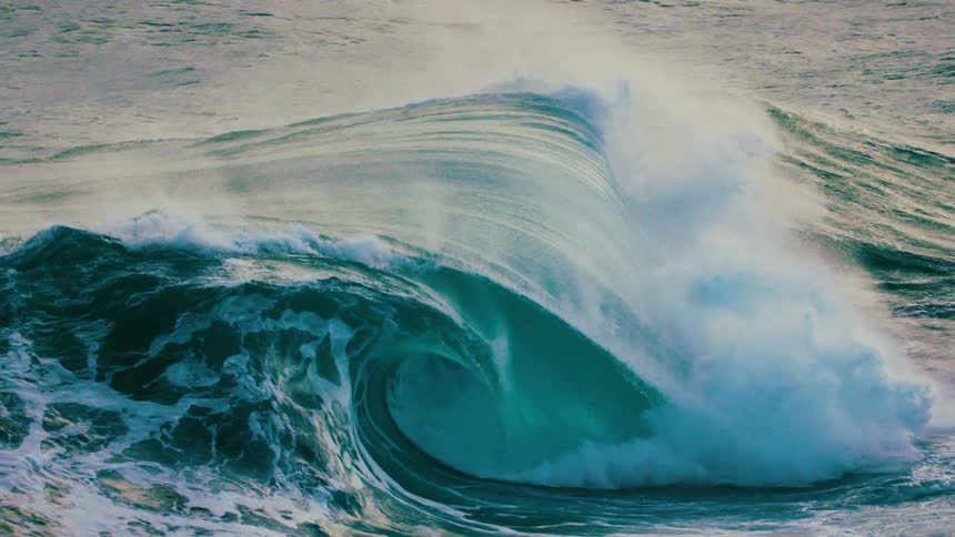 A majestic, powerful turquoise ocean wave rises and crashes in dramatic ultra slow motion