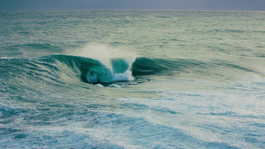 A mesmerizing slow motion view of a powerful turquoise ocean wave building and crashing spectacularly