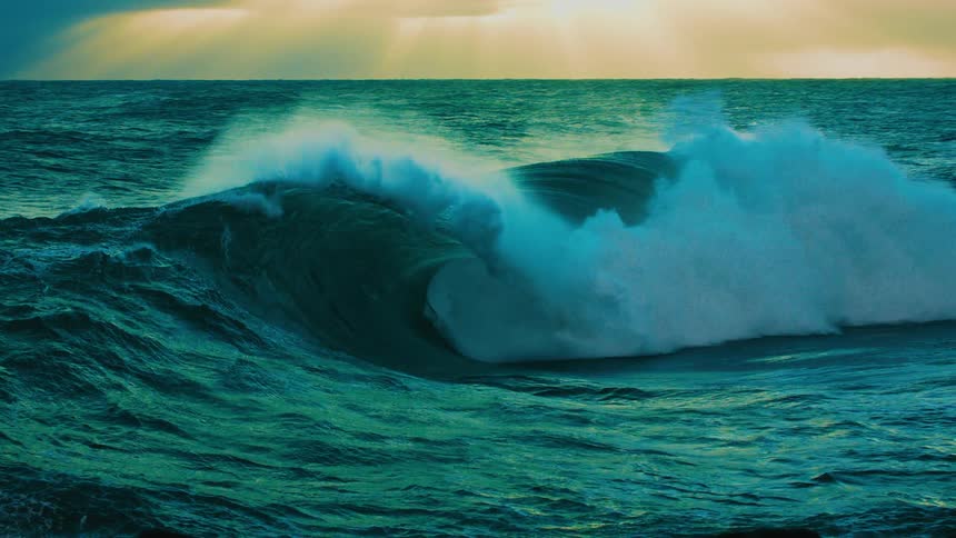A majestic teal-colored ocean wave powerfully curls and crashes in dramatic ultra slow motion